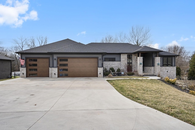 prairie-style house featuring a garage, concrete driveway, stone siding, and a front yard