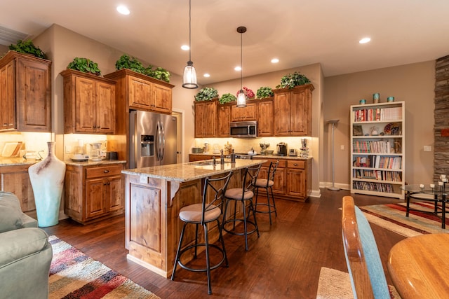 kitchen with light stone countertops, brown cabinetry, stainless steel appliances, and dark wood-style flooring