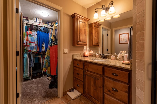 bathroom featuring tile patterned floors, a walk in closet, vanity, and baseboards