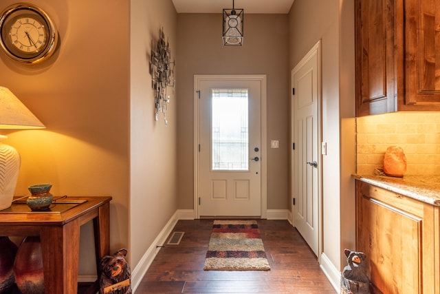 doorway featuring dark wood-type flooring, visible vents, and baseboards