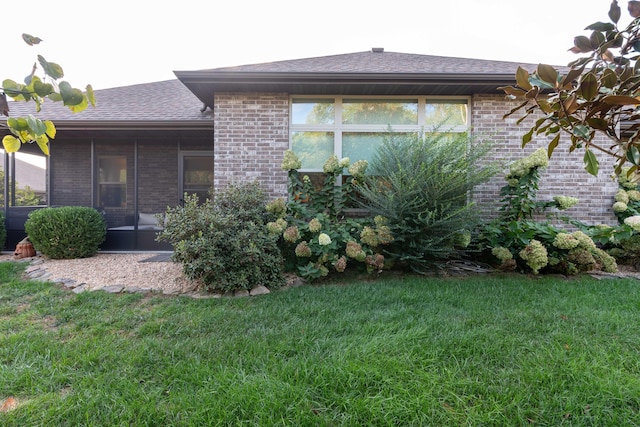 back of house with a shingled roof, a lawn, and brick siding