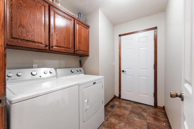 clothes washing area featuring cabinet space, baseboards, washer and clothes dryer, and a textured ceiling