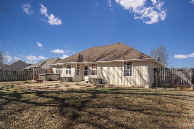 back of property with a patio, a lawn, a fenced backyard, and a hot tub