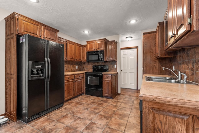 kitchen with black appliances, tasteful backsplash, brown cabinets, and a sink