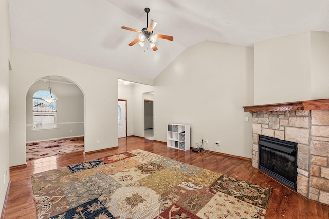 living room with a fireplace, lofted ceiling, ceiling fan, wood finished floors, and baseboards