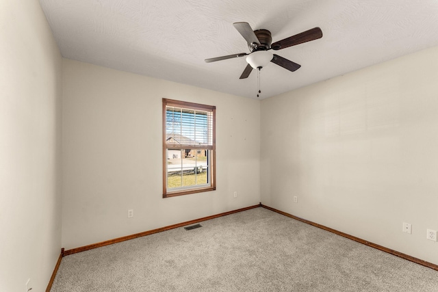 carpeted empty room with visible vents, ceiling fan, a textured ceiling, and baseboards