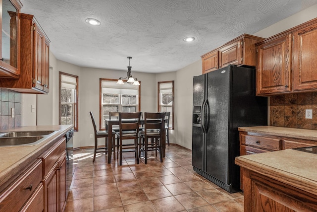 kitchen featuring tasteful backsplash, brown cabinets, a sink, and black appliances