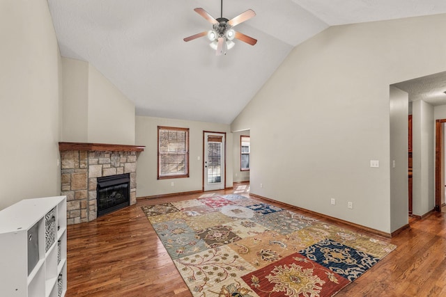 living area featuring ceiling fan, a fireplace, baseboards, and wood finished floors