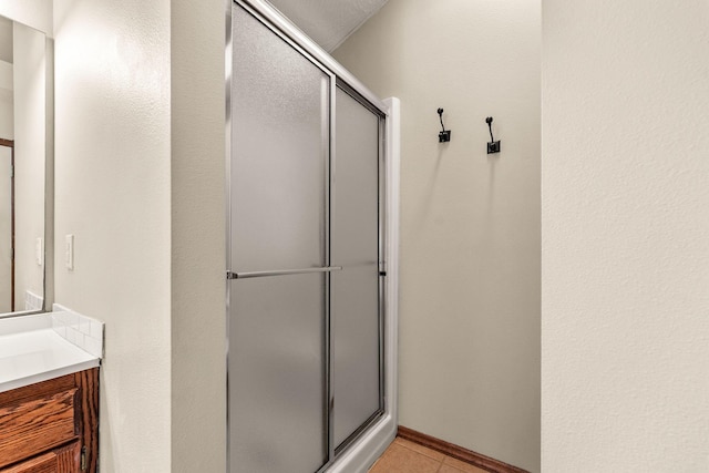 bathroom with a stall shower, vanity, and tile patterned floors