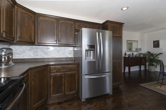 kitchen with dark countertops, stainless steel fridge, decorative backsplash, and dark wood-style flooring