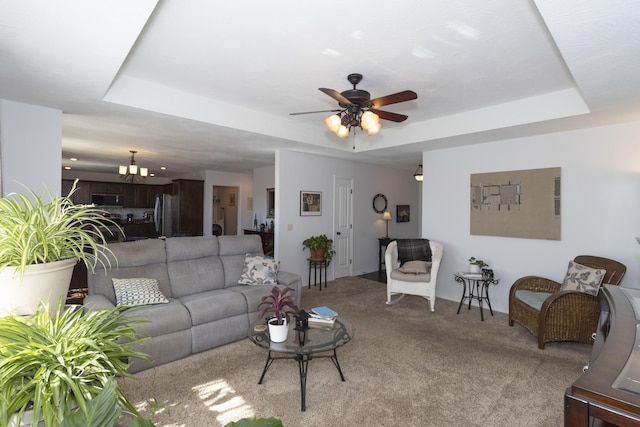 living room featuring light carpet, a raised ceiling, and ceiling fan with notable chandelier