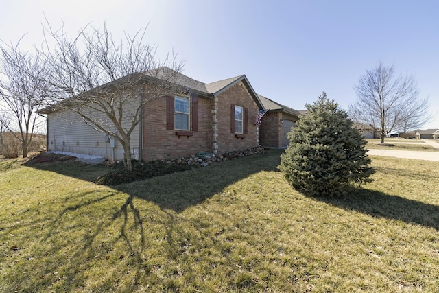 view of side of home with a garage, a yard, and brick siding