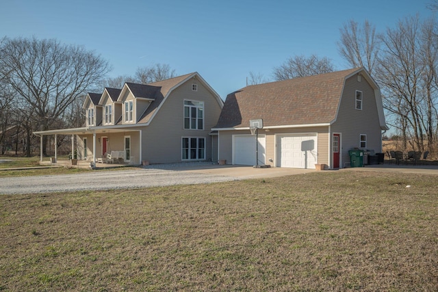 view of front of home with covered porch, driveway, a front lawn, and a gambrel roof