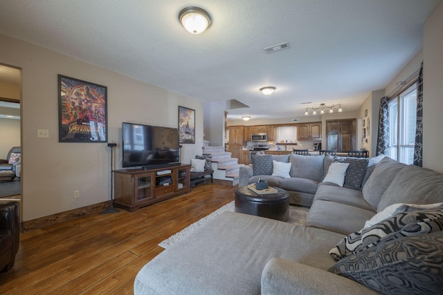 living room with baseboards, a textured ceiling, visible vents, and dark wood-type flooring