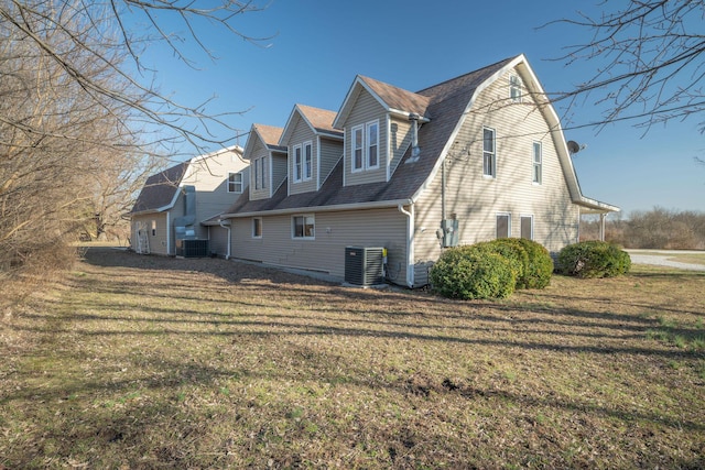 view of property exterior with central AC, a yard, and a gambrel roof