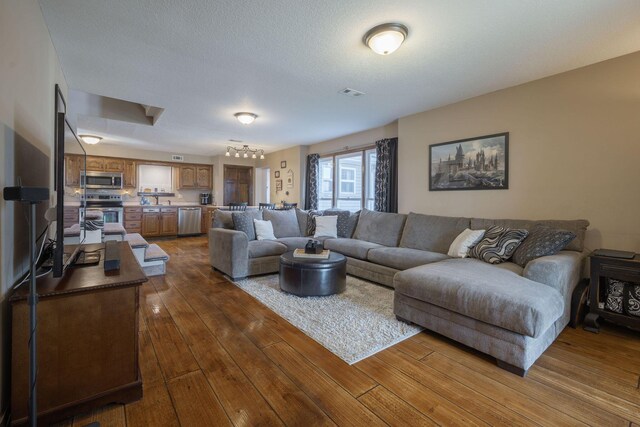 living area featuring a textured ceiling, dark wood-style flooring, and visible vents