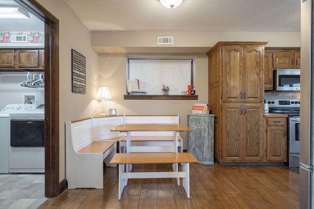 dining space featuring a textured ceiling, washer / clothes dryer, wood finished floors, and visible vents