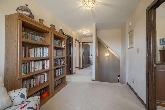 corridor with a textured ceiling, carpet, and baseboards