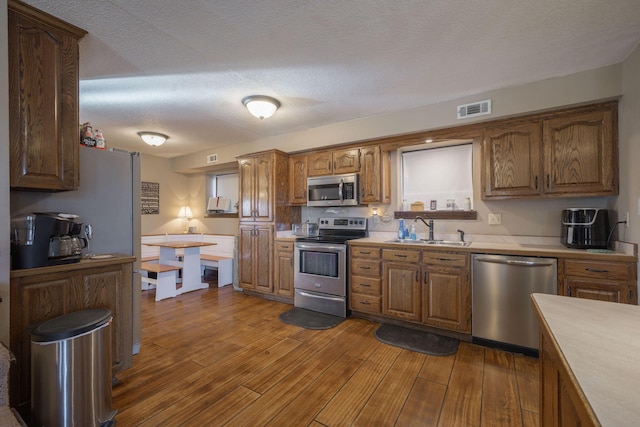 kitchen featuring visible vents, dark wood finished floors, stainless steel appliances, light countertops, and a sink