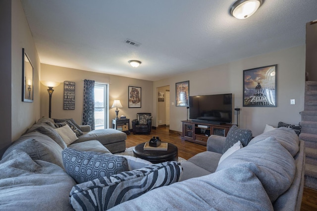 living area with a textured ceiling, wood finished floors, and visible vents