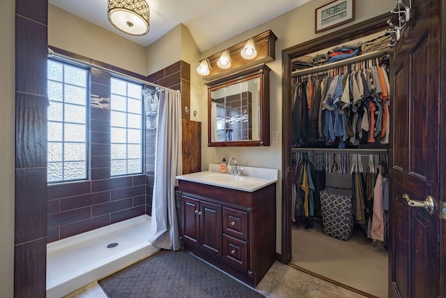 full bath featuring a healthy amount of sunlight, a tile shower, and vanity