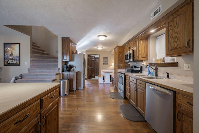 kitchen with light countertops, visible vents, appliances with stainless steel finishes, dark wood-type flooring, and a sink