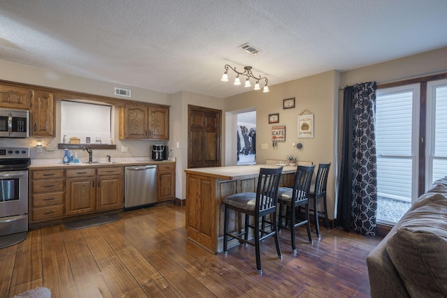 kitchen featuring appliances with stainless steel finishes, light countertops, visible vents, and a sink