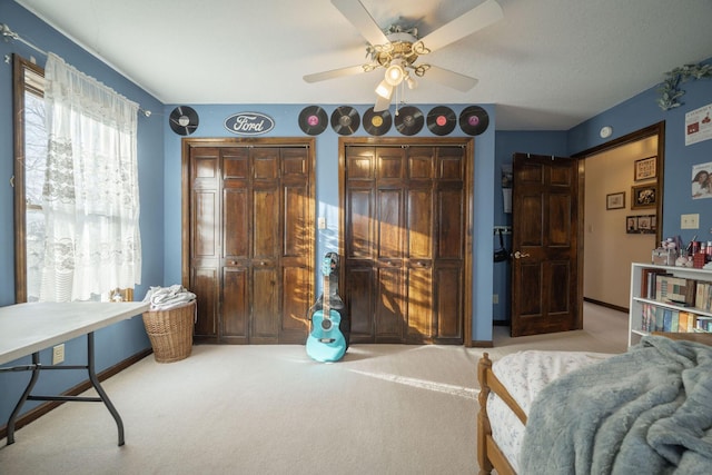 bedroom with a ceiling fan, baseboards, two closets, and light colored carpet