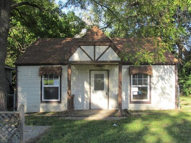 view of front of house featuring a front lawn and roof with shingles