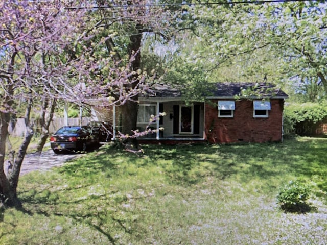 view of front of house featuring a porch, crawl space, brick siding, and a front lawn