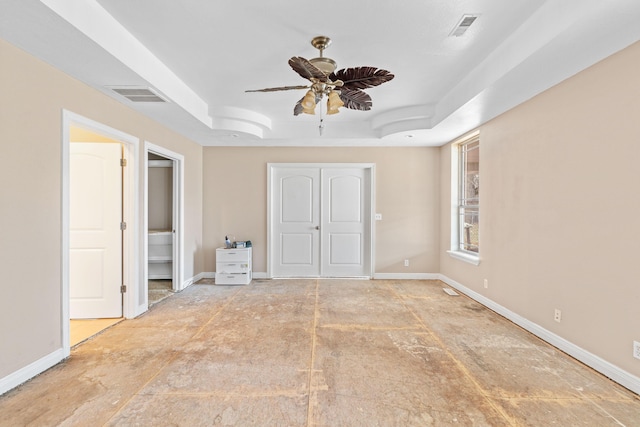 unfurnished bedroom featuring visible vents, a tray ceiling, ceiling fan, and baseboards