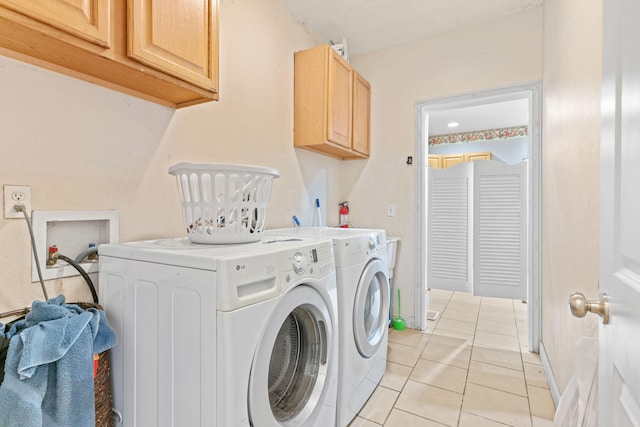 laundry area featuring light tile patterned flooring, cabinet space, baseboards, and separate washer and dryer