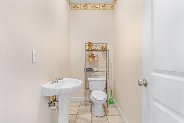 bathroom featuring toilet, tile patterned flooring, and baseboards