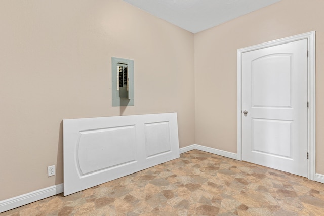 laundry room featuring stone finish flooring, electric panel, and baseboards