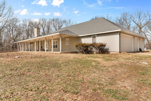 exterior space with covered porch, roof with shingles, a chimney, and a yard