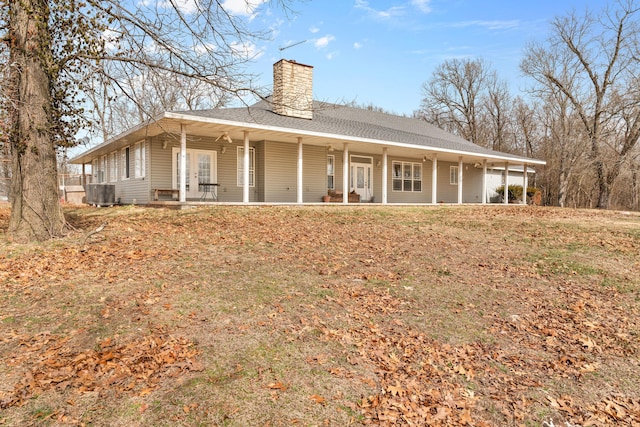 back of property featuring covered porch, roof with shingles, and a chimney