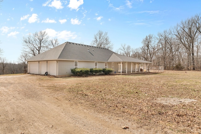 view of side of home featuring a garage and dirt driveway