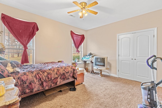 carpeted bedroom with a ceiling fan, baseboards, visible vents, and a closet