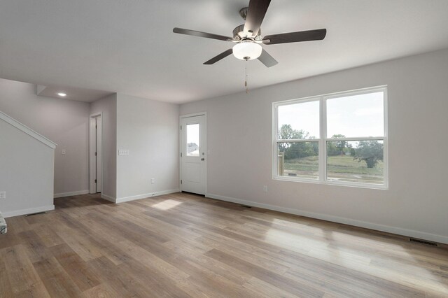 unfurnished living room featuring light wood finished floors, visible vents, baseboards, and a ceiling fan