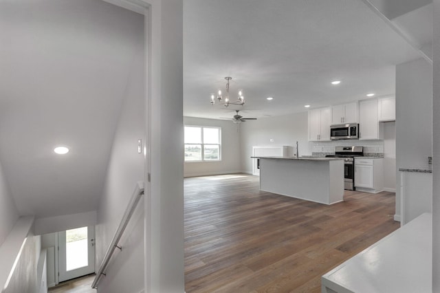 kitchen featuring white cabinetry, open floor plan, appliances with stainless steel finishes, decorative backsplash, and light wood finished floors