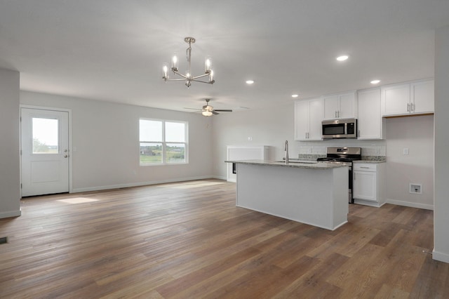 kitchen with light wood-style flooring, appliances with stainless steel finishes, open floor plan, white cabinetry, and a sink