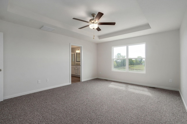 spare room featuring baseboards, visible vents, ceiling fan, carpet, and a tray ceiling