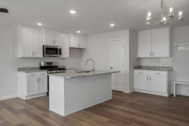 kitchen featuring stainless steel appliances, a sink, white cabinetry, light stone countertops, and dark wood finished floors