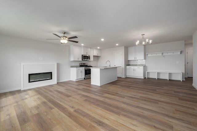 kitchen featuring wood finished floors, stainless steel appliances, a sink, and open floor plan