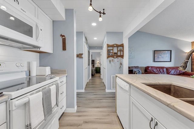 kitchen featuring light stone counters, white appliances, a sink, white cabinets, and light wood-type flooring