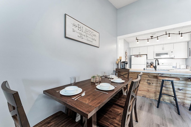 dining area with rail lighting and wood finished floors