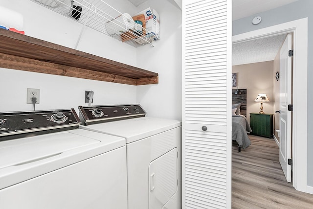 laundry room with a textured ceiling, laundry area, light wood-style flooring, and washer and dryer