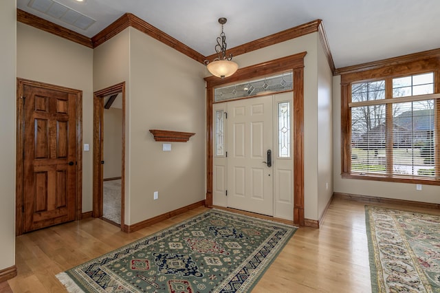 entryway featuring baseboards, light wood-type flooring, visible vents, and crown molding