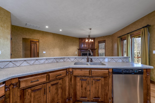 kitchen featuring light countertops, visible vents, brown cabinetry, a sink, and dishwasher