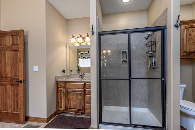 full bathroom featuring toilet, a stall shower, baseboards, and vanity